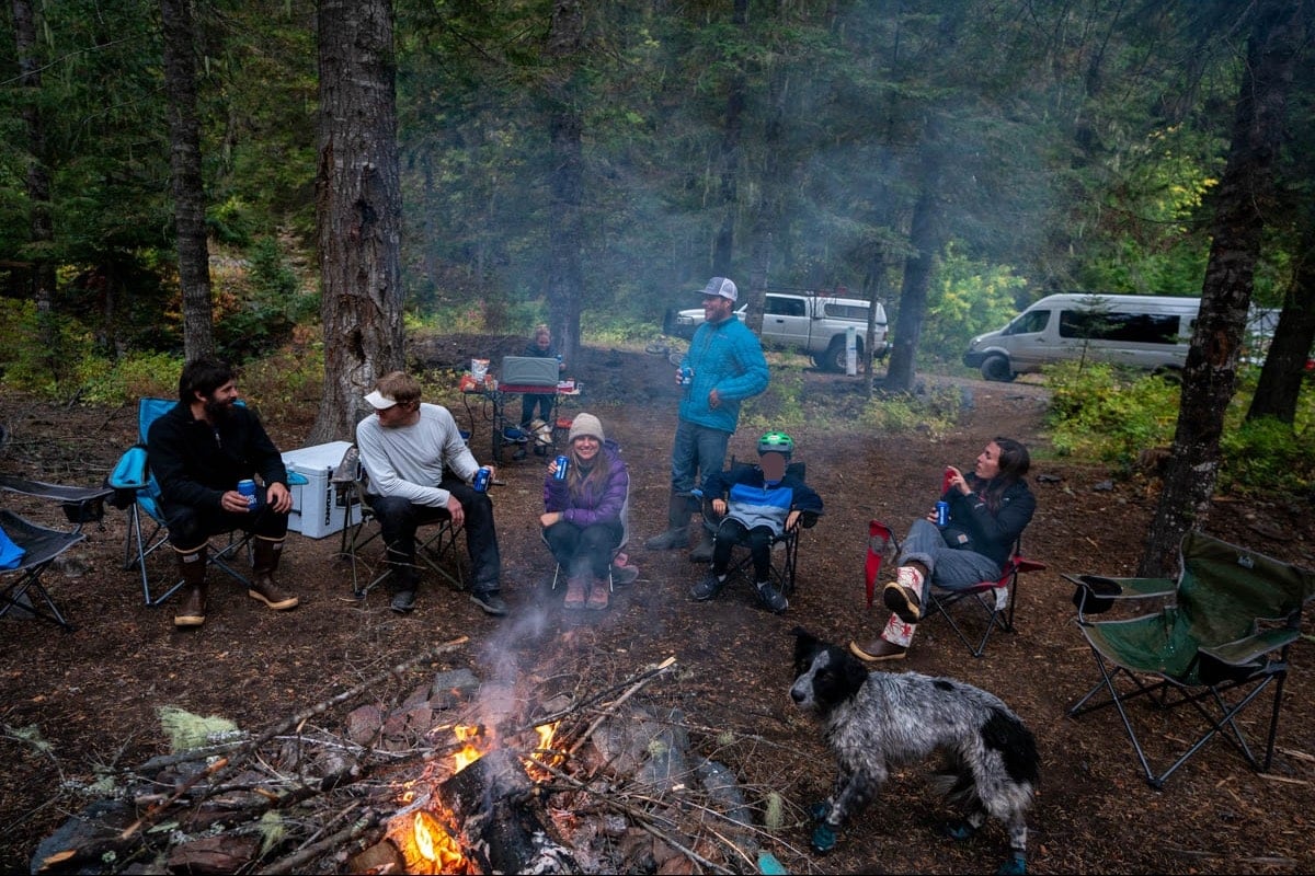 group of people sitting around campfire on a rainy day